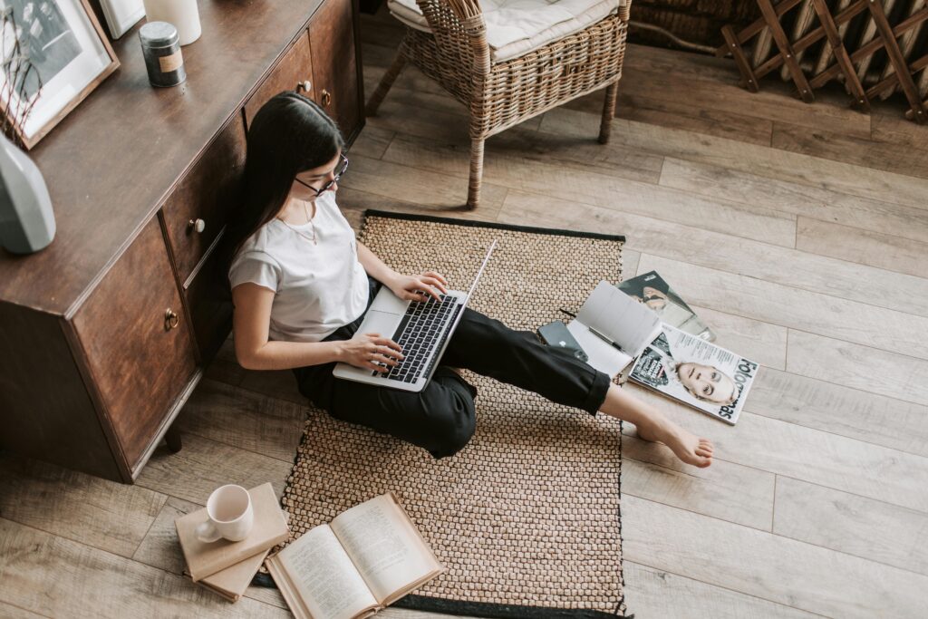 pexels-photo-4050351-4050351 Casual home workspace with a woman using a laptop, surrounded by books and magazines.